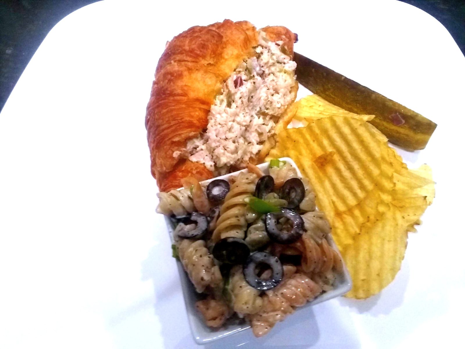 Chicken salad croissant with pasta salad, pickle and chips